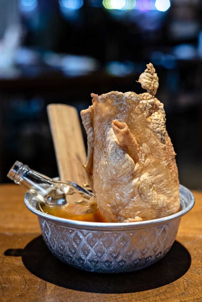 Err in Bangkok, Thailand. Signature dish Chicken Movie, crispy chicken skin with hot sauce.