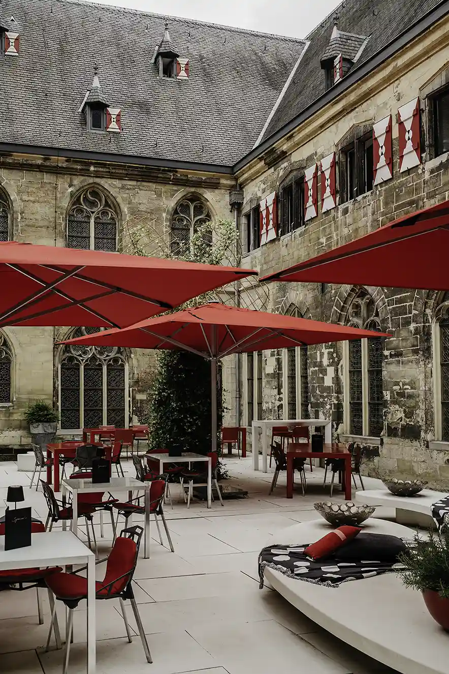 Binnenplaats van het klooster waar het Kruisherenhotel Maastricht is gevestigd met rode tafels