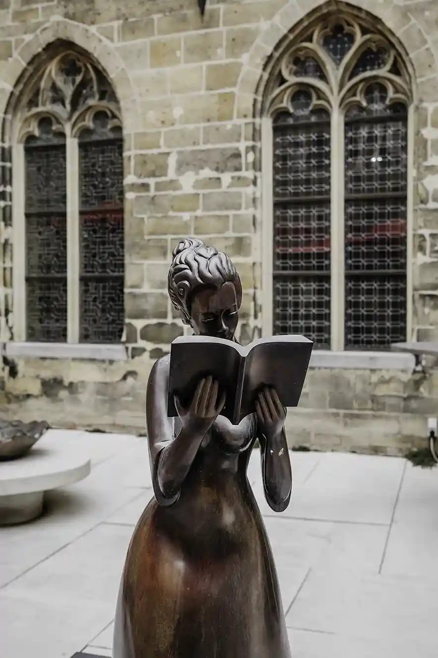 Beeld van een lezende vrouw op de binnenplaats van het Kruisherenhotel Maastricht