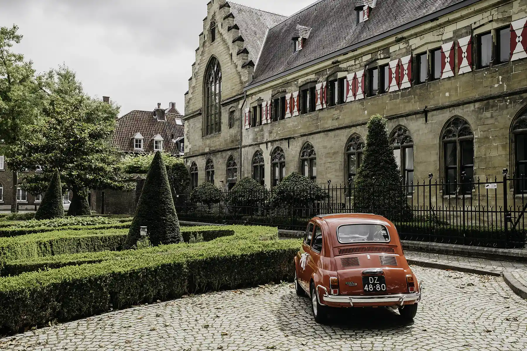 Schattig rood autootje voor het Kruisherenhotel in Maastricht, Nederland. Een oud klooster en gotische kerk van buitenaf gezien.